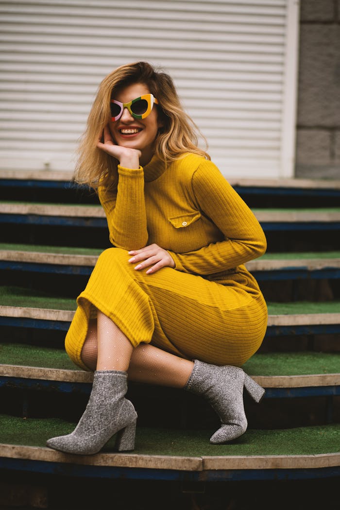 about-04 Stylish woman in yellow dress and sunglasses posing on steps. Modern fashion portrait.