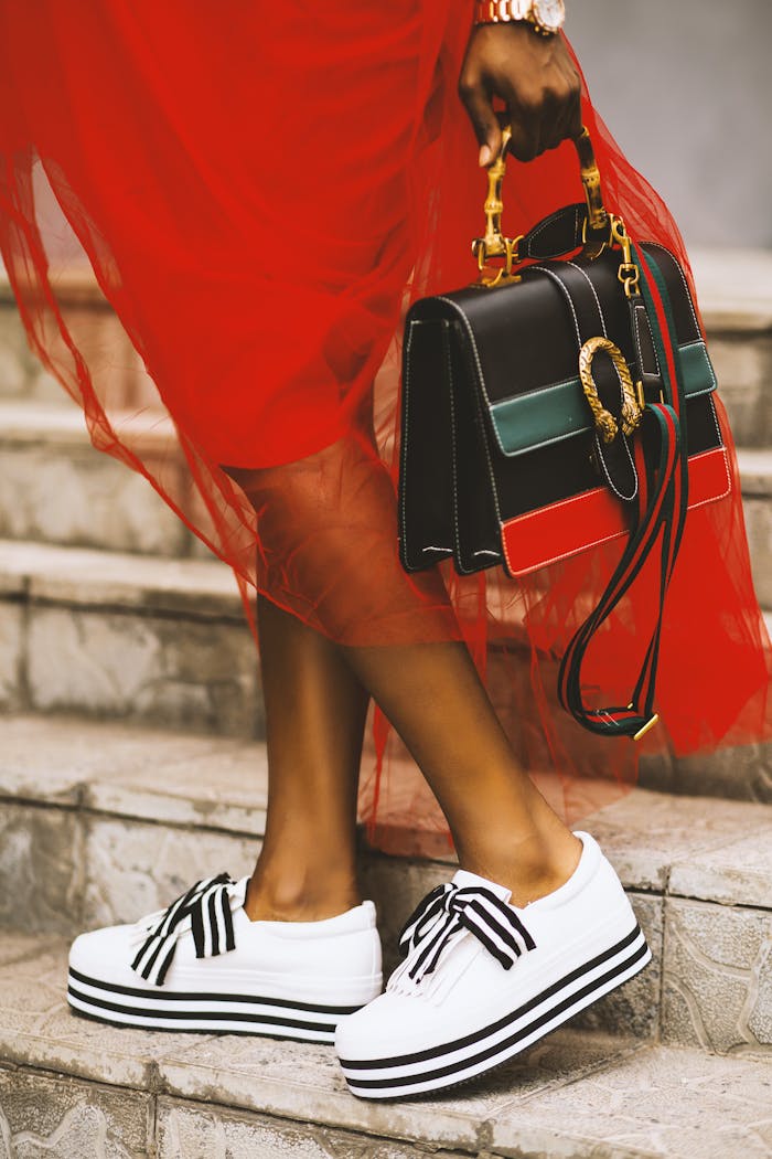 menu-11 Elegant pose featuring modern sneakers and a chic designer handbag on stone steps.