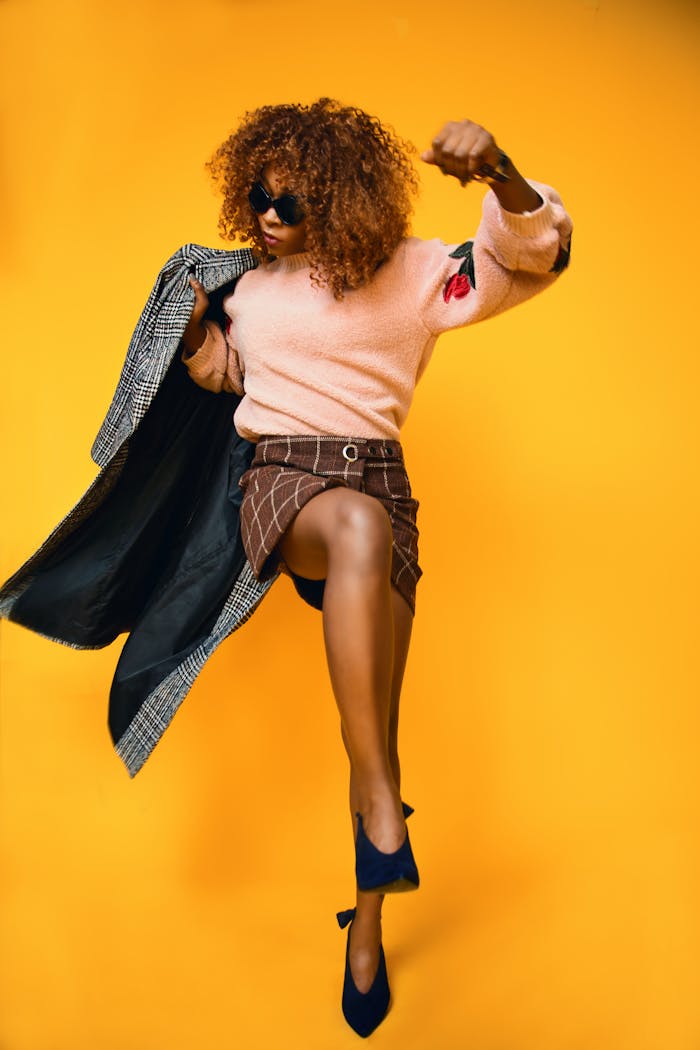 menu-03 Stylish woman in a dynamic fashion pose against a vibrant orange background.